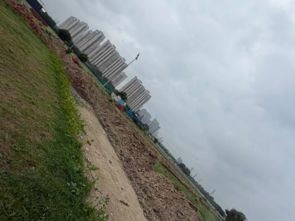 Residential project site with green landscaping, construction materials and high-rise buildings in the background